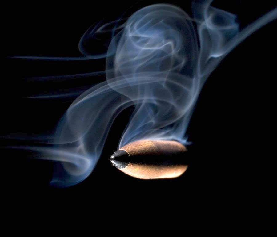 Bullet with smoke that is rising from it on a black background