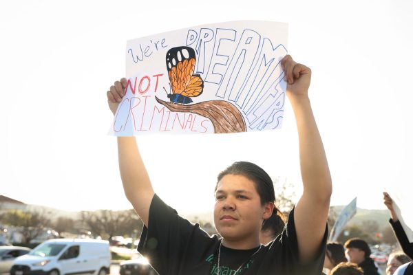 AMERICAN DREAMERS - Traveling back to campus, freshman Diego Campoverde continues to hold a poster high, reading "We're Dreamers, NOT Criminals." The illustration of a monarch butterfly has become a symbol in anti-ICE protests, alluding to the migration of the insect, which is often celebrated for its beauty.