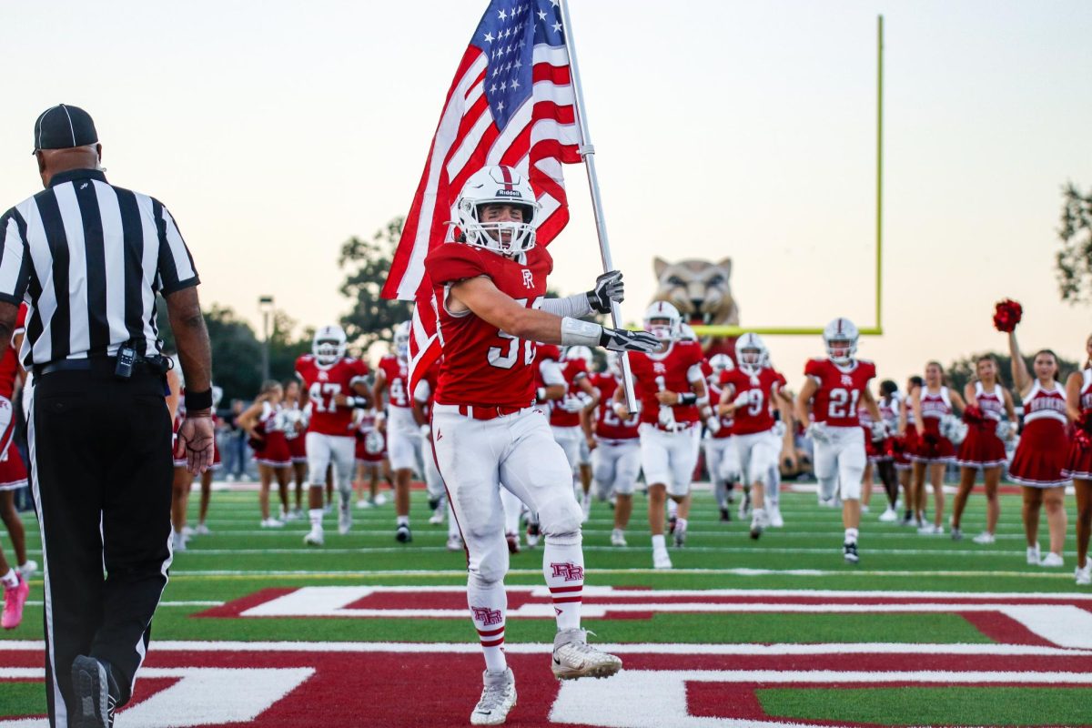 Senior Hayden Roady leads the team out of the tunnel with the American flag in preparation for the kickoff. 