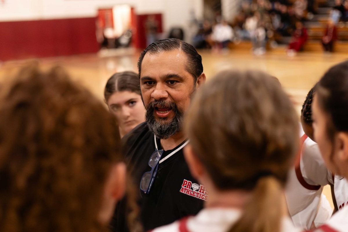 PEP TALK - Varsity women’s basketball head coach Mark Martinez fires up the team before tipoff, urging players to play with pride. Martinez has led the program since 2021. 