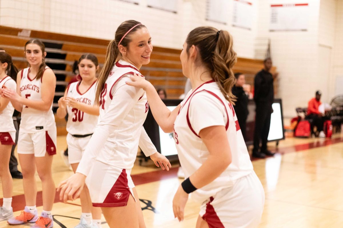 OFF THE SHOULDER - Senior Samantha Martinez greets the team’s starters with a unique routine as she and junior Tori Holbrook share a handshake before tipoff, setting the game with confidence.